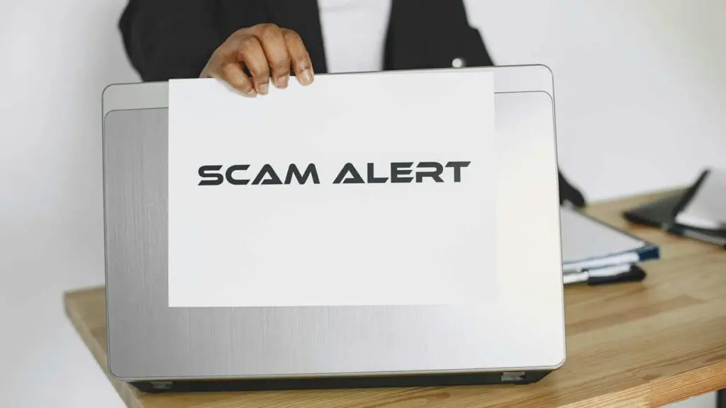 Scam alert graphic on back of open computer for fake Facebook profile story