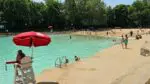 Wide shot of Naperville's Centennial Beach with lifeguard station and kids walking next to water