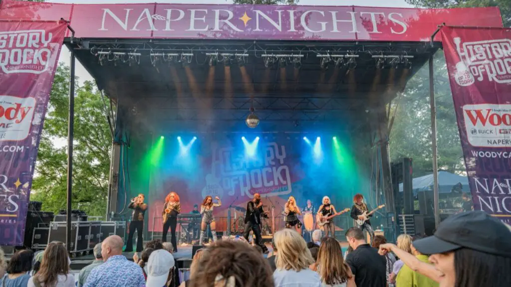 FILE image of band on stage with crowd cheering at Naper Nights summer concert series at Naper Settlement