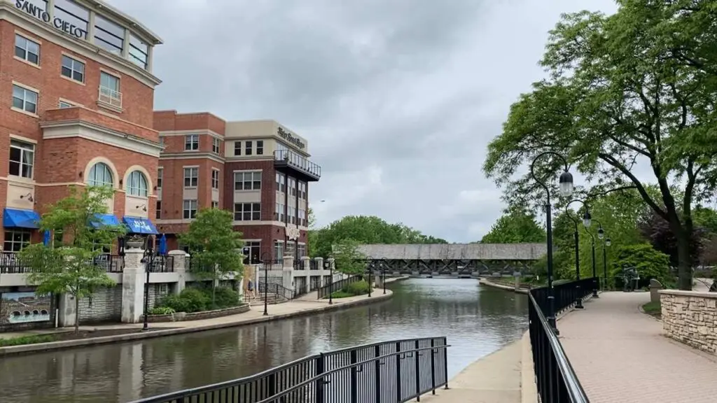 Beauty shot of the Naperville Riverwalk with Water Street buildings, DuPage River, covered bridge in view