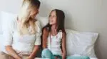 Parent and child sitting on a bed looking at each other