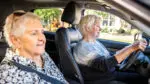 Two older women are seated in a car.