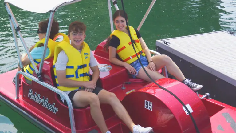 Two people wearing yellow life vests sit in a paddleboat in the Naperville quarry.