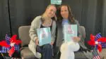 Heather Lewandowski and her daughter, Ava Lewandowski, smile for a picture while holding up their book "The Best Summer Day," during a book signing in Aurora, IL.