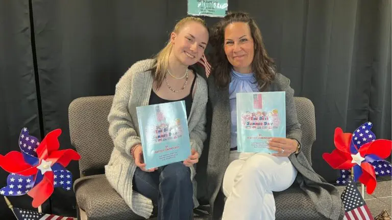 Heather Lewandowski and her daughter, Ava Lewandowski, smile for a picture while holding up their book "The Best Summer Day," during a book signing in Aurora, IL.