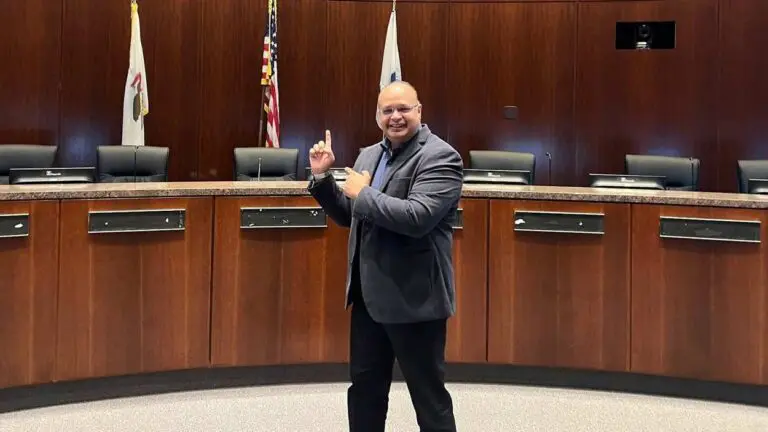 Ashfaq Syed standing in front of the Naperville City Council dais.