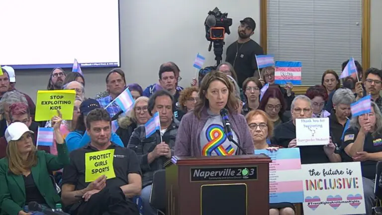 Community members at Naperville School District 203 board meeting weighing in on transgender athlete controversy with both pro and con signs on the issue in background