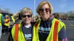 Two women volunteers wearing reflective vests and t-shirts that say Duly Good.