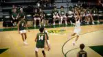 Jonah Aranda hits the ball backwards as The Waubonsie Valley Volleyball team watches.