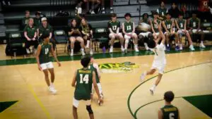 Jonah Aranda hits the ball backwards as The Waubonsie Valley Volleyball team watches.