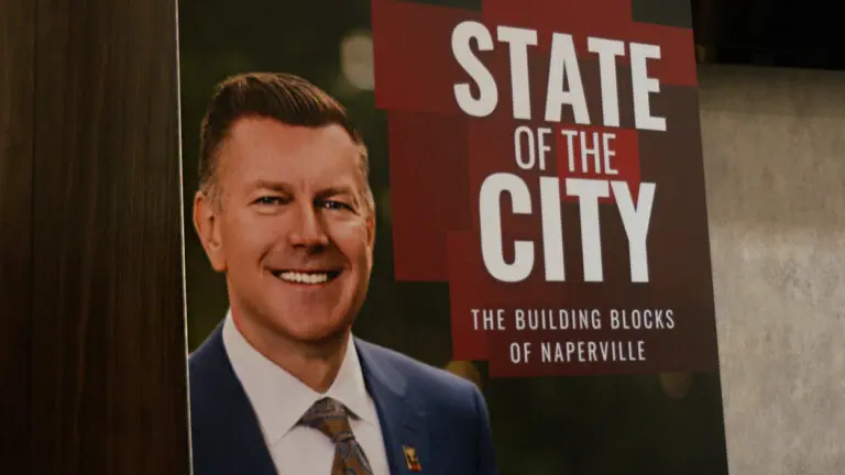 sign of naperville mayor Scott Wehrli with "state of the city: the building blocks of Naperville" over his shoulder