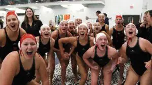 Naperville Central girls water polo flexes to the camera after beating Waubonsie Valley.