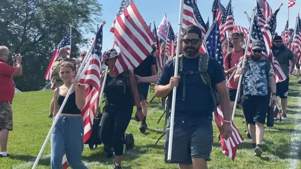 People carry flags down Rotary Hill. Naperville Salute canceled for summer 2025