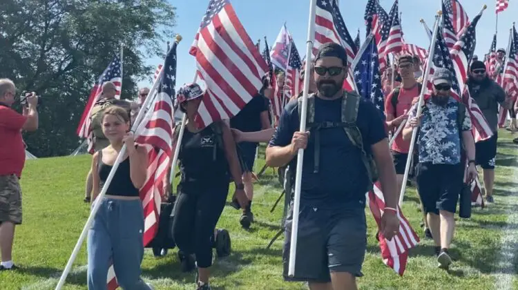 People carry flags down Rotary Hill. Naperville Salute canceled for summer 2025