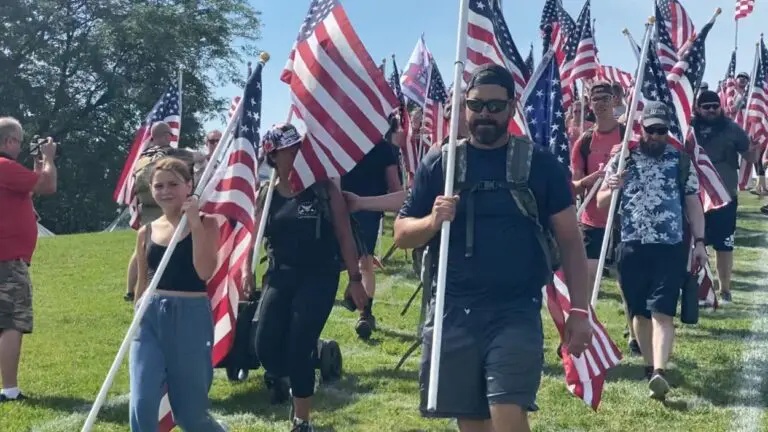 People carry flags down Rotary Hill. Naperville Salute canceled for summer 2025