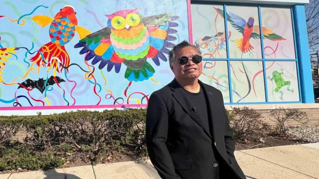 Naperville artist Rich Lo standing in front of colorful mural he painted at DuPage Children's Museum