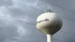 Cell phone tower components atop Naperville water tower with power lines in foreground