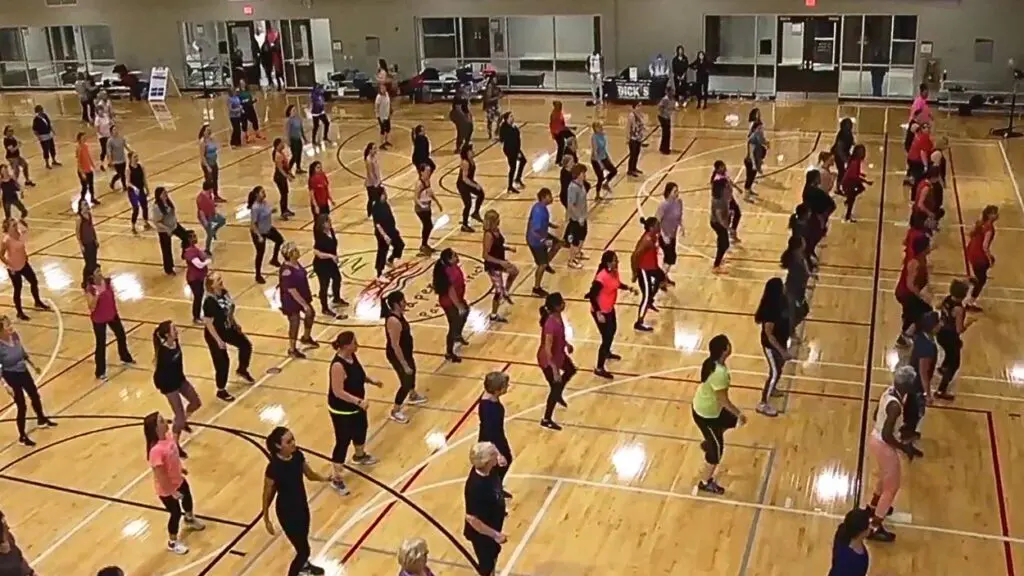 Wide shot of Naperville Park District gym with group of women in lines working out in the indoor space