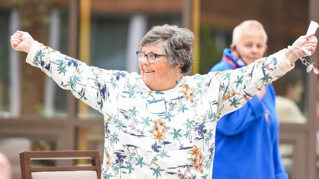 A woman stands with her arms outstretched and holds a set of keys.