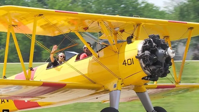 Bright yellow open top plane with two passengers inside at Cavalcade of Planes