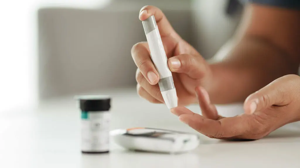 Close up of a woman's hands that are using a lancing kit to test blood sugars.
