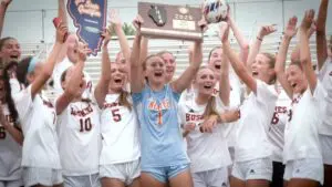 Naperville North girls soccer smiles and cheers with the SuperSectional plaque after beating Wheaton Warrenville South.
