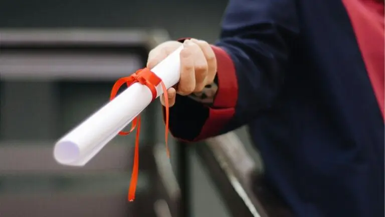 Rolled up piece of paper tied with bow held in hand - like a diploma - for story on National Merit Scholarship winners