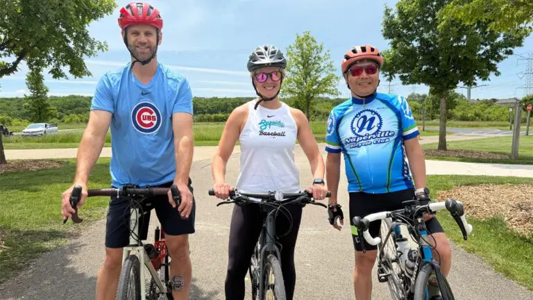 Zac Larson, creator of the Solstice Century bike ride stands over his bike alongside two participants Ganerdene Gantumer and Katie Peseski