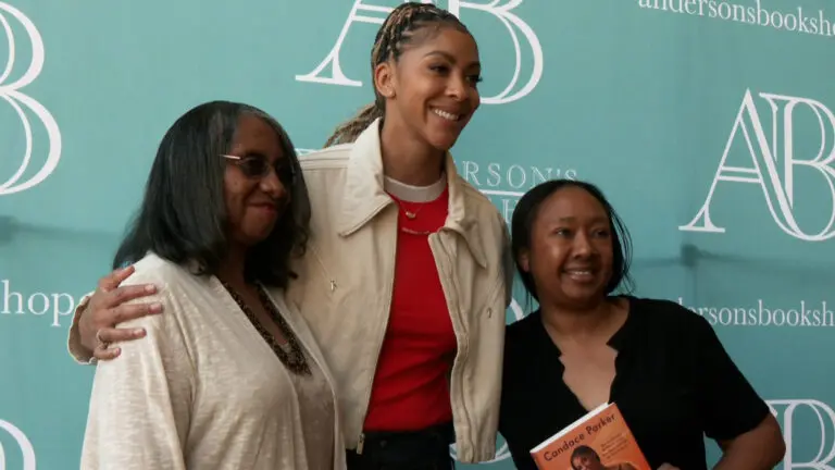 Former WNBA star Candace Parker with arms around two fans posing for a photo