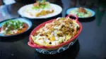 A close up of nachos layered with cheese, salsa, and beef.