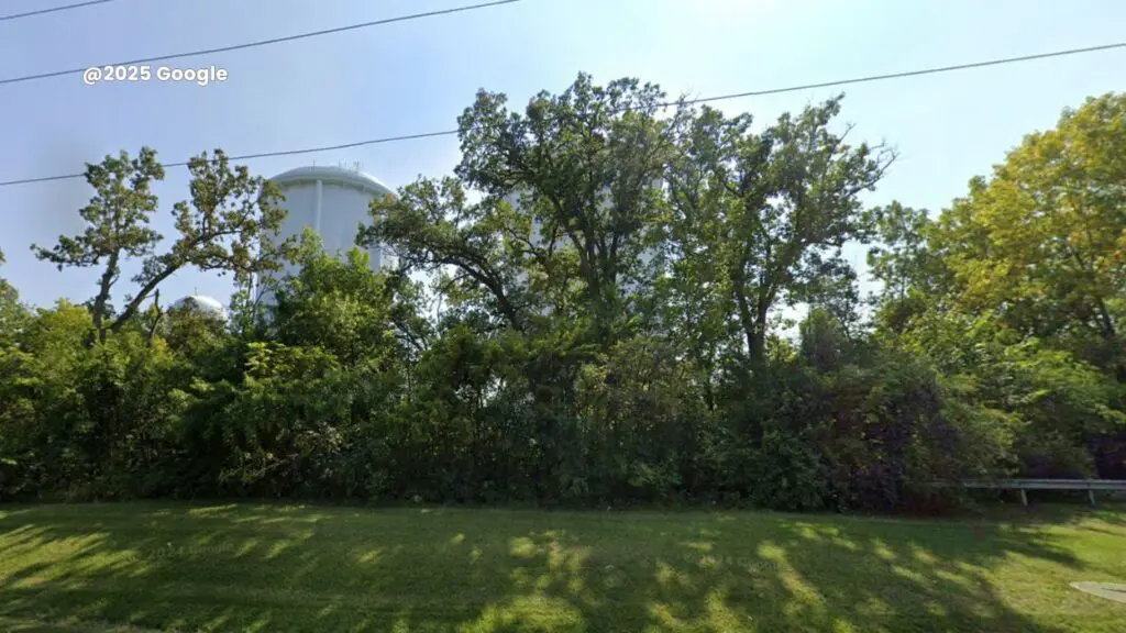 Land being considered for sale by water commission - trees and water towers in background