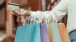 Outstretched arm of woman holding shopping bags and a credit card