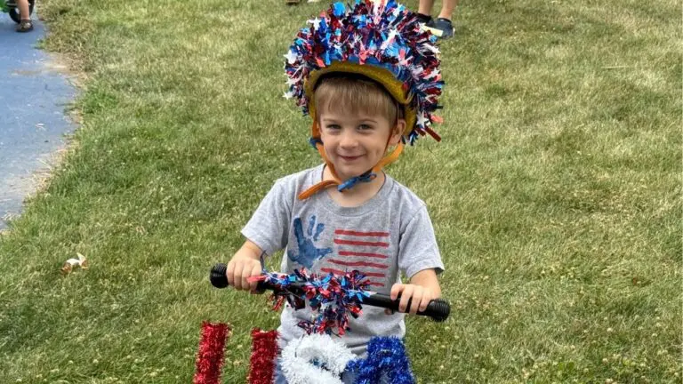 A little boy on a bicycle smiles for a picture as he prepares to take part in the Fourth of July bike parade.