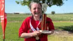 A Special Olympics athlete wearing a medal and holding her first place trophy.