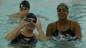 Waubonsie Valley girls swimmers smiling before match against Metea Valley
