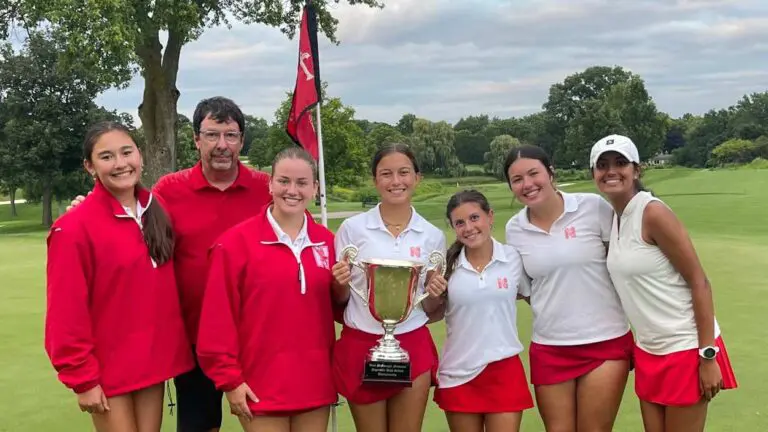 Naperville Central girls golf team holds the Vern McGonagle City Championship trophy on the 18th green at Naperville Country Club.
