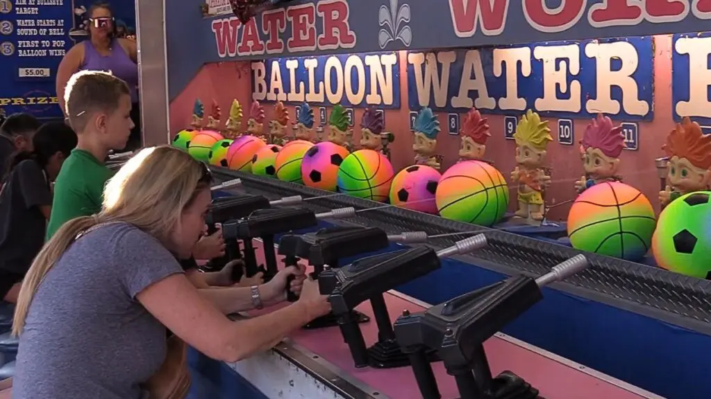 Woman and boy playing water spray gun carnival game at Last Fling in Naperville