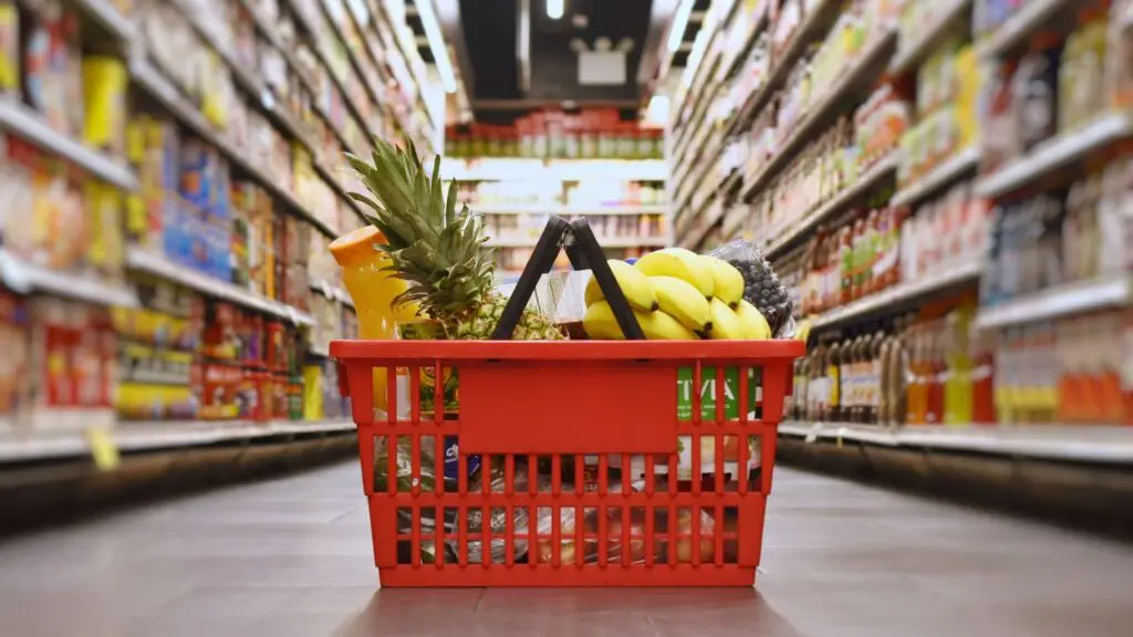 Basket of groceries sitting in aisle in grocery store