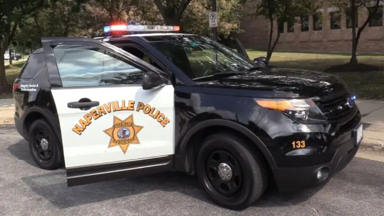 Wide shot of Naperville Police Department squad car with door open and lights on