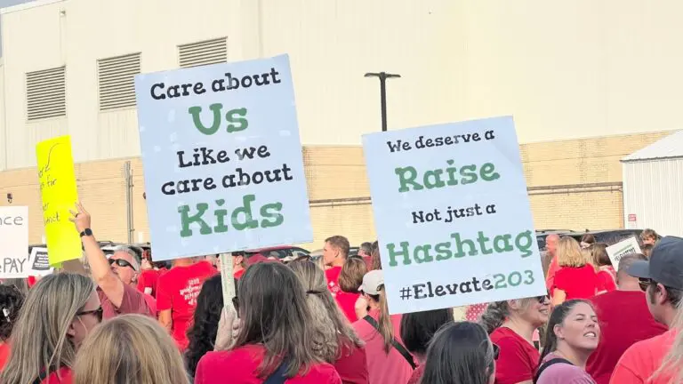Two signs at the rally reading, "Care about us like we care about kids" and "We deserve a raise not just a hashtag"
