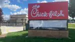 Close up of Chick fil A sign with new Chick fil A restaurant in background on left
