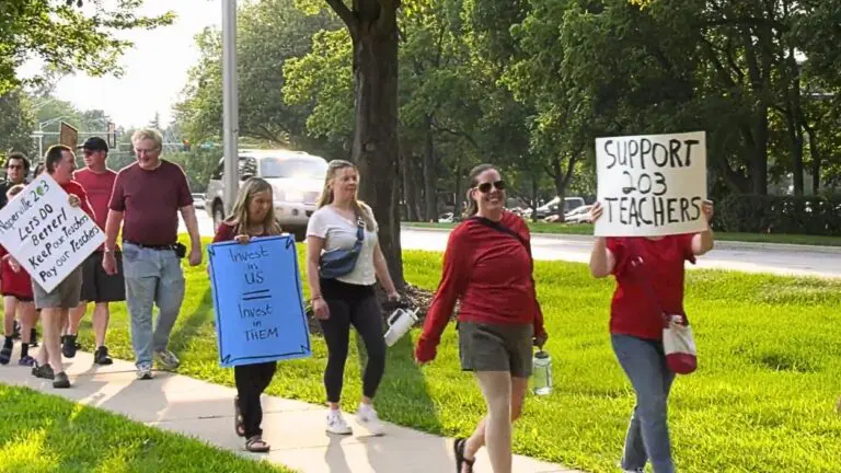 Naperville School District 203 teachers or supporters walk with signs at rally