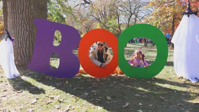 I giant statue that reads "BOO" with the B in purple, the first O in orange and the second O in green. A mom and child smile through the letter O.