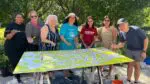 Community members take part in painting a new mural being unveiled in Downtown Naperville.