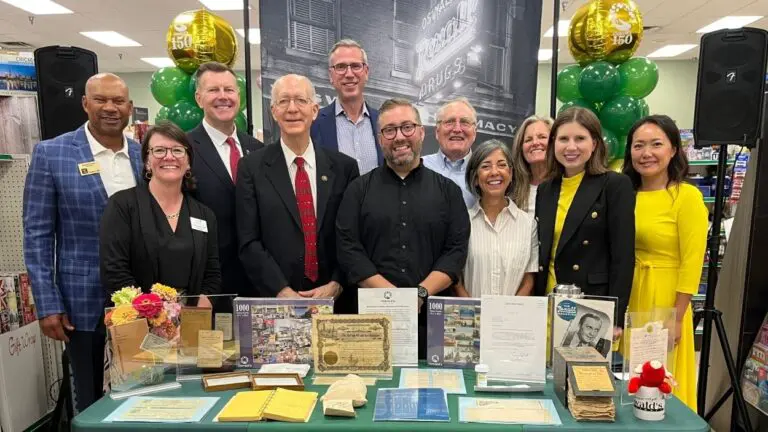Alex Anderson of Oswald's Pharmacy smiles for a picture with local and state law makers as they celebrate the pharmacy's 150th anniversary.
