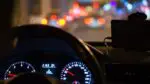Dashboard of car looking out through windshield at traffic at night