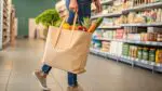 Person carrying bag full of groceries in store