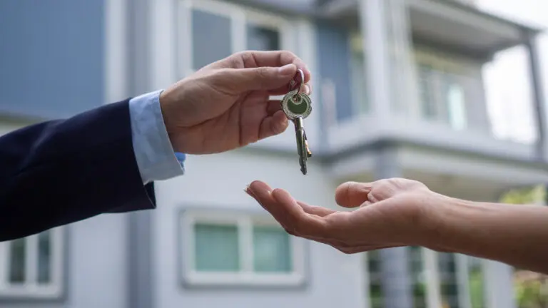 Close up of a seller's hand giving a set of keys to a home buyer.