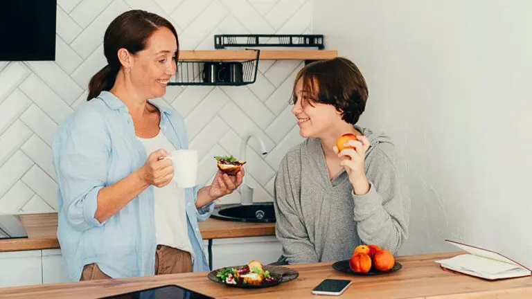 Mom talks to her teenage son over breakfast at a kitchen counter
