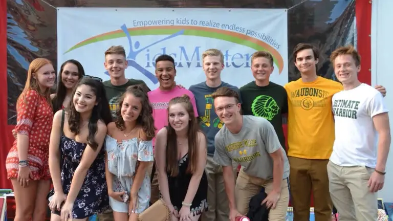 A group of high school students pose in front of a KidsMatter banner.